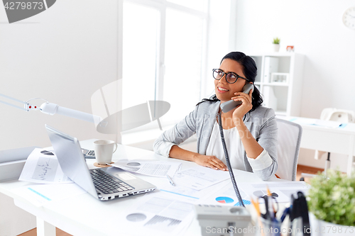 Image of businesswoman calling on desk phone at office