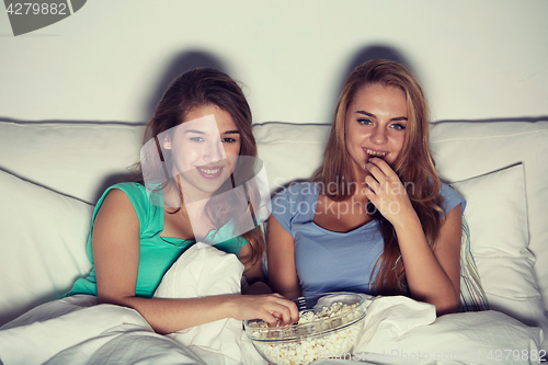 Image of happy friends with popcorn and watching tv at home