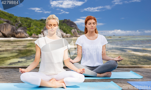 Image of women meditating in yoga lotus pose outdoors