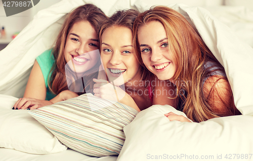 Image of happy young women in bed at home pajama party