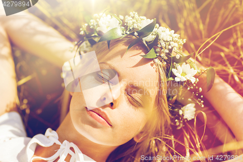 Image of happy woman in wreath of flowers lying on straw