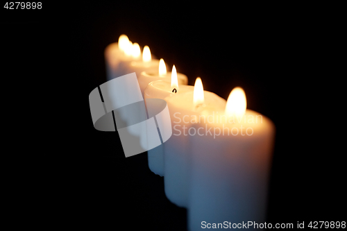 Image of candles burning in darkness over black background