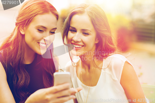 Image of happy young women with smartphone at outdoor cafe