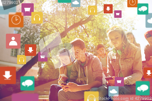 Image of group of teenage friends with smartphones outdoors