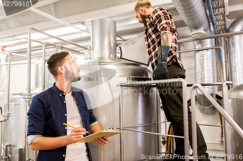 Image of men with clipboard at craft brewery or beer plant