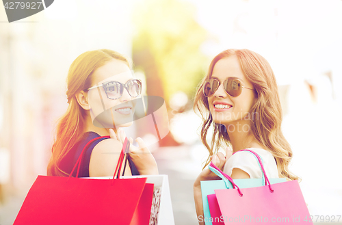 Image of happy young women with shopping bags in city