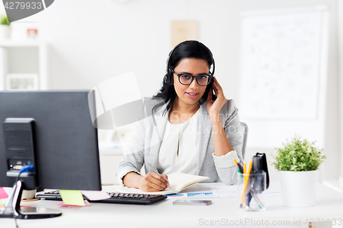 Image of businesswoman with headset and notebook at office