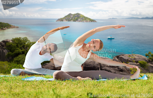 Image of happy couple making yoga exercises outdoors