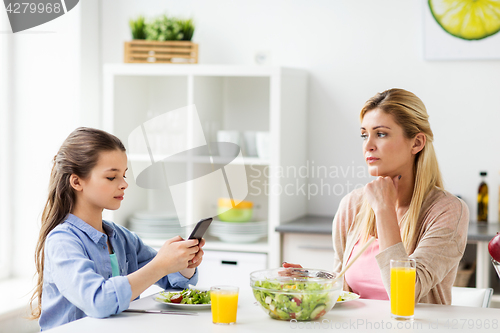 Image of sad woman looking at her daughter with smartphone