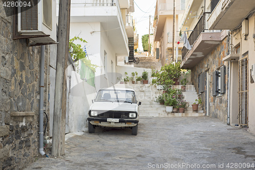 Image of Old rusty white car parked in the street