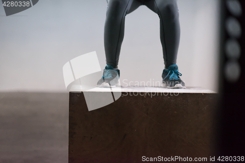 Image of black woman is performing box jumps at gym