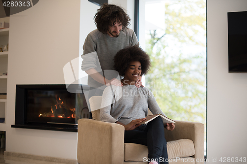 Image of multiethnic couple hugging in front of fireplace