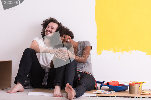 Image of young multiethnic couple relaxing after painting