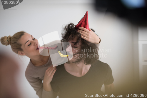 Image of couple in party hats blowing in whistle