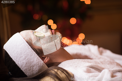 Image of woman is getting facial clay mask at spa