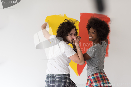 Image of multiethnic couple painting interior wall