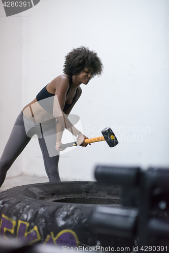 Image of black woman workout with hammer and tractor tire