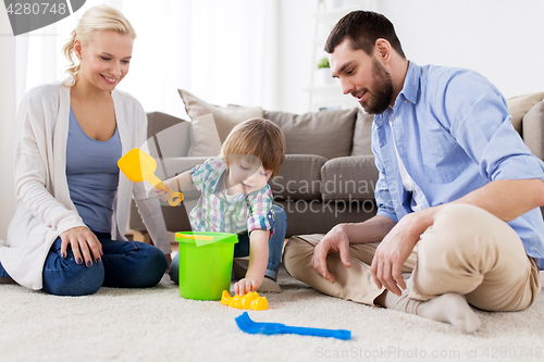 Image of happy family playing with beach toys at home
