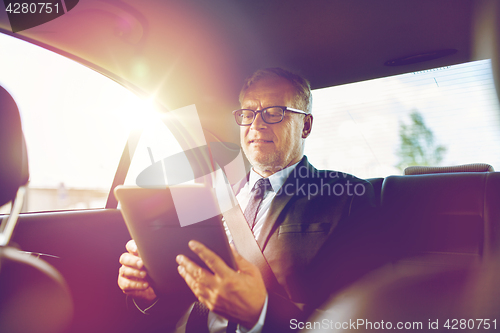 Image of senior businessman with tablet pc driving in car