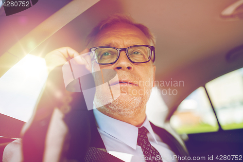 Image of senior businessman calling on smartphone in car