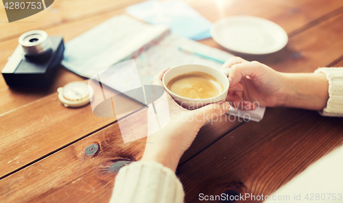 Image of close up of hands with coffee cup and travel stuff