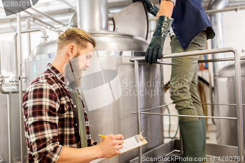 Image of men with clipboard at craft brewery or beer plant