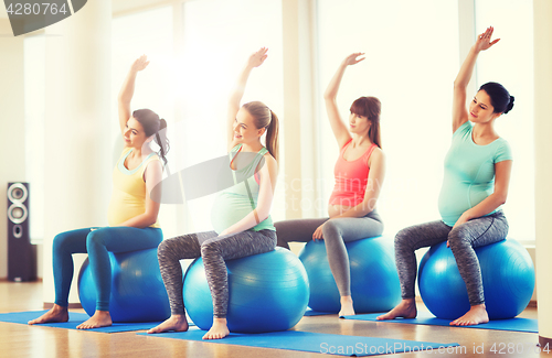 Image of happy pregnant women exercising on fitball in gym