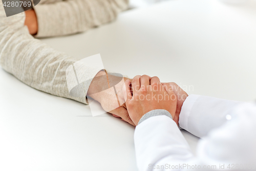 Image of close up of doctor holding old man hand