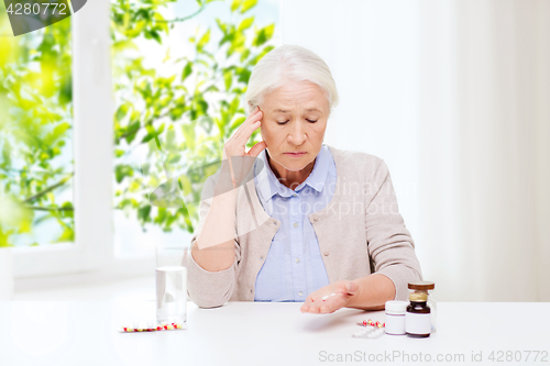 Image of senior woman with water and medicine at home