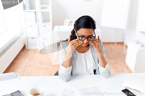 Image of businesswoman rubbing tired eyes at office