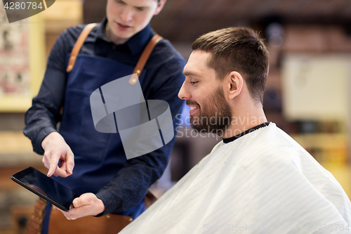 Image of barber showing tablet pc to man at barbershop