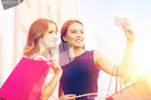 Image of happy women with shopping bags and smartphone