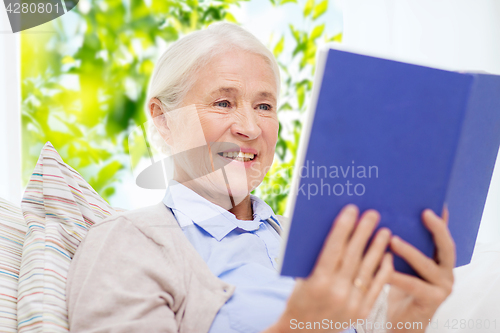 Image of happy smiling senior woman reading book at home