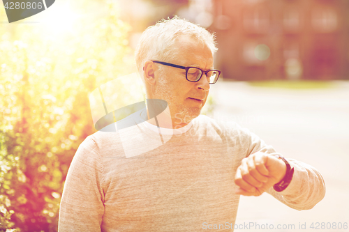 Image of senior man checking time on his wristwatch