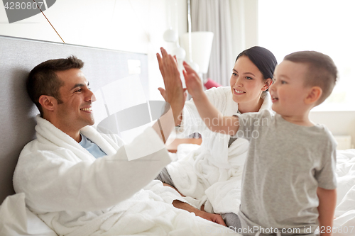 Image of happy family in bed at home or hotel room