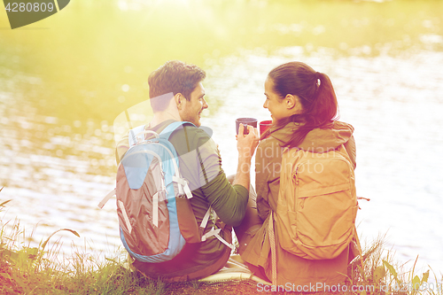 Image of happy couple with cups drinking in nature