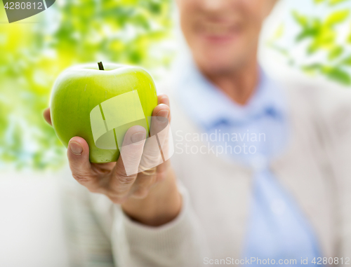 Image of close up of senior woman hand holding green apple