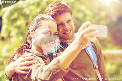 Image of couple with backpacks taking selfie by smartphone