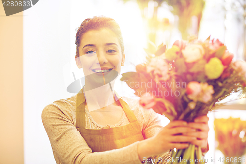 Image of smiling florist woman making bunch at flower shop