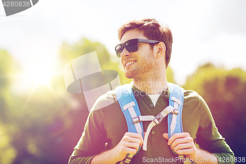 Image of happy young man with backpack hiking outdoors