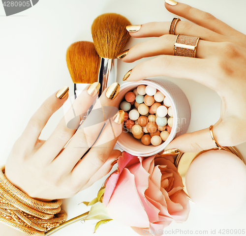 Image of woman hands with golden manicure and many rings holding brushes,