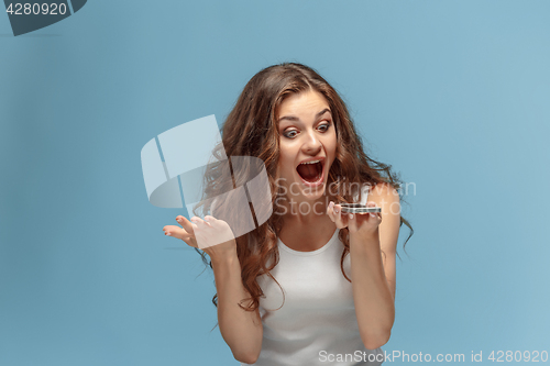 Image of Shocked woman looking at mobile phone on green background