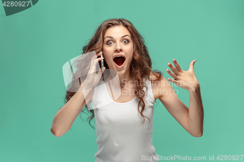 Image of Shocked woman looking at mobile phone on green background