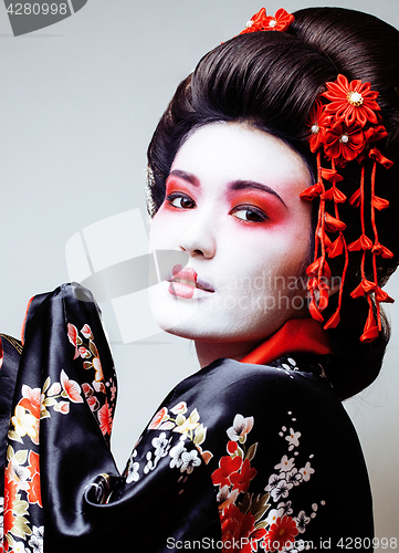 Image of young pretty geisha in black kimono among sakura, asian ethno close up