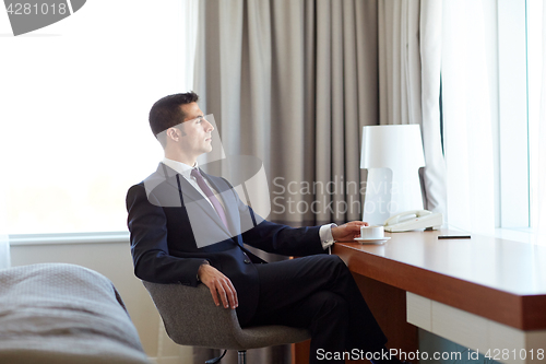 Image of businessman drinking coffee at hotel room