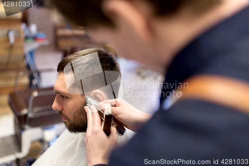 Image of man and barber hands with trimmer cutting hair