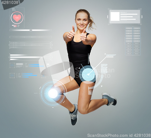 Image of woman in sportswear jumping and showing thumbs up