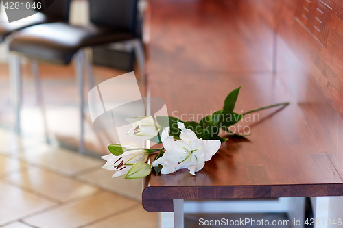 Image of white lily on bench at funeral in church