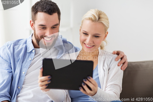 Image of smiling happy couple with tablet pc at home