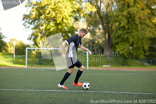 Image of soccer player playing with ball on football field